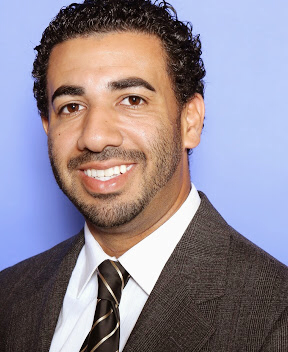 Professional man in a suit smiling against a blue backdrop.