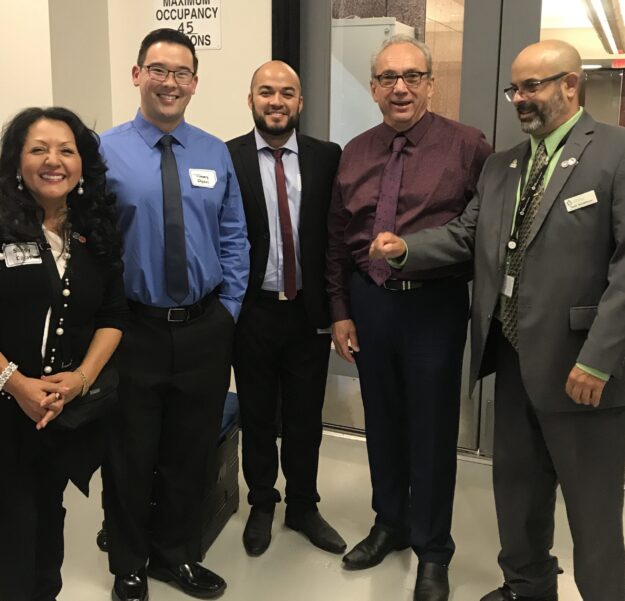 Five professionals posing together indoors, dressed in business attire. Five professionals posing together indoors, dressed in business attire.
