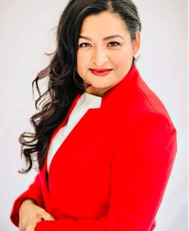 Professional woman in a red blazer smiles confidently.